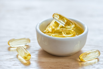 Cod liver oil omega 3 gel capsules in bowl on floor wood