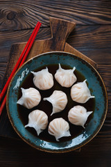 Top view of a glass plate with chinese dim-sums in soy sauce