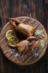 Whole baked quails in a rustic wooden setting, high angle view