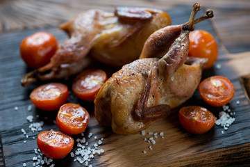 Whole baked quails and tomatoes, selective focus, close-up