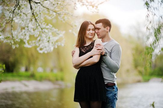 Young couple in love outdoor background lake with blossom tree
