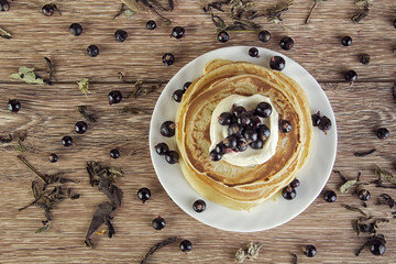 Pancakes with the cream and blackcurrant on the wooden table