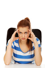Worried teenage woman sitting behind desk