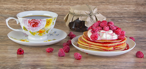 Pancakes with the cream, jam and  raspberry on the wooden table