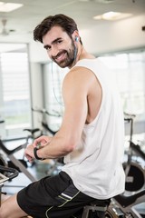 Obraz na płótnie Canvas Smiling man on exercise bike using smartwatch