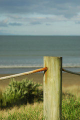 Rope fence pole close to beach marks protected areas of sand dunes.