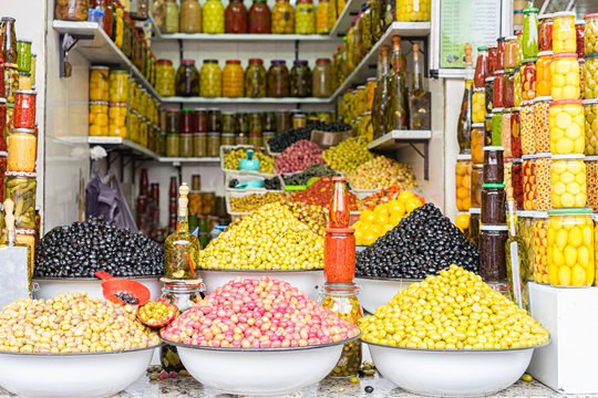 Market stall selling fresh olives and bottled food in the main souk of Marrakesh, Morocco.