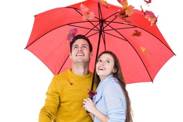 Happy couple under an umbrella throwing leaves