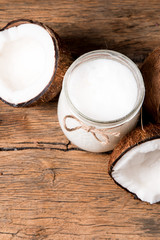 coconut oil and fresh coconuts on old wooden table