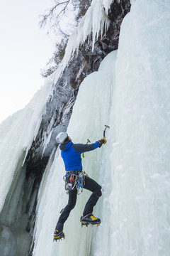 Man climbing up on frozen waterfall