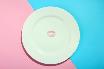 a large plate on pink and blue background with track in the centre of the kissing of lips with red lipstick