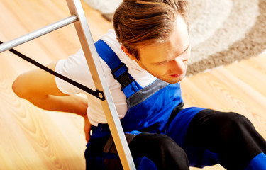 Handyman fell from a ladder and sitting on the floor with backache 