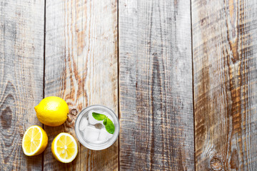 glass with ice and lemon, mint on wooden table