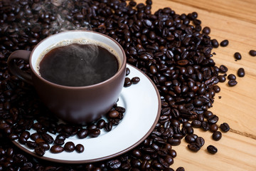 Coffee cup and coffee beans on a wood background.