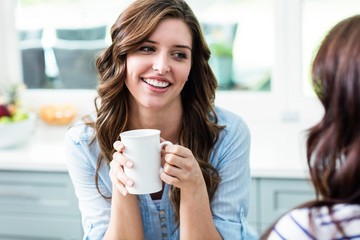 Smiling friends holding coffee mugs while sitting at table