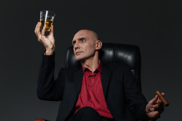 Businessman with glass of whiskey and cigar sitting in chair