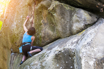 The girl climbs on the rock.