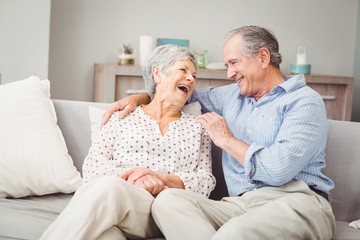 Romantic senior couple laughing while sitting on sofa