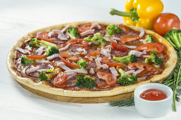 tasty pizza on a wooden board with beautiful vegetables and sauc