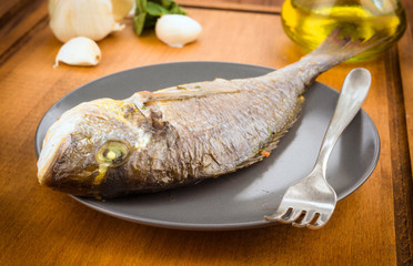 Whole Roasted bream on plate, on wood