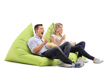 Couple eating popcorn seated on beanbags