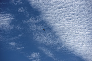 Airplane flying at a height against a brilliant blue sky filled