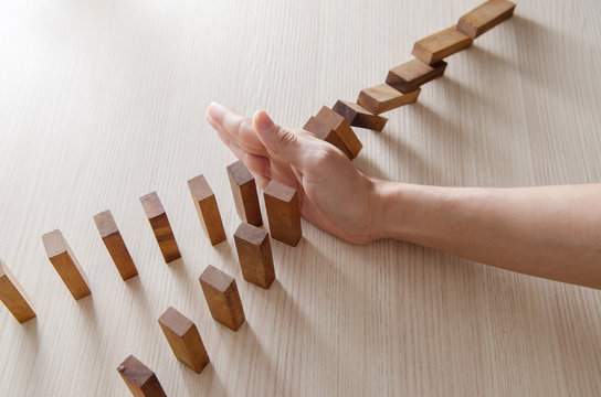 Close up woman hand stopping the domino wooden effect concept for business.