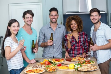 Happy multi-ethnic enjoying alcohol and pizza at table