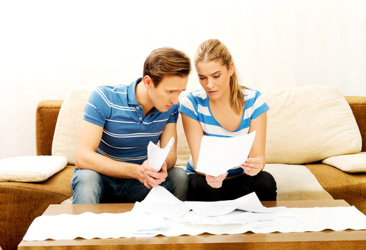 Worried couple after calculating bills sitting at home