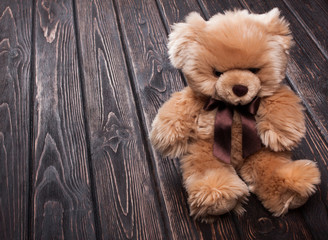 Brown teddy bear on wooden boards.