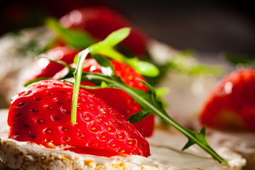 Multigrain rice cakes with strawberries fruit , soft mascarpone cheese and arugula for healthy breakfast.