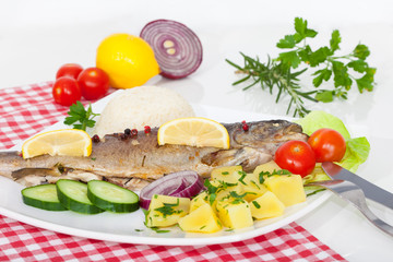Fototapeta na wymiar Cooked fish with vegetables, herbs and lemon on the plate