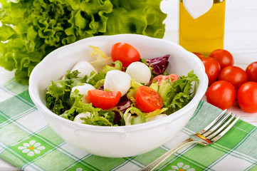 Fresh vegetable salad with tomatoes and feta in white bowl.