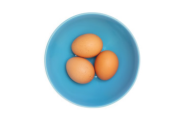 Three eggs in a blue bowl on a clear white background
