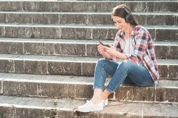 Fototapeta na wymiar Young hipster sitting on stairs with smartphone and headphones