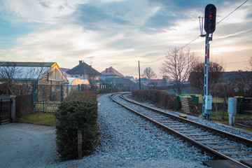 Red semaphore signal by the railroad outgoing right between houses.
