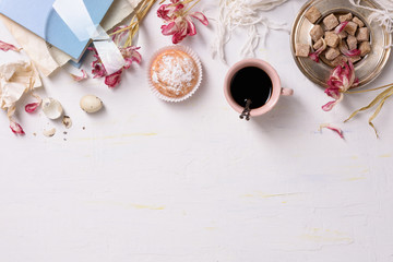 Breakfast background: cup of coffee, cakes, brown sugar and flowers, over white. Top view, copy space.