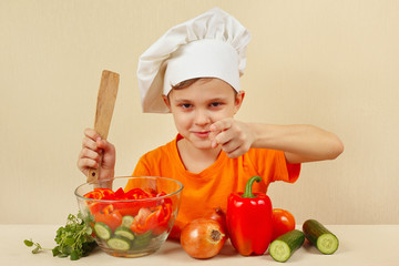 Young smiling chef shows how to cook a vegetable salad