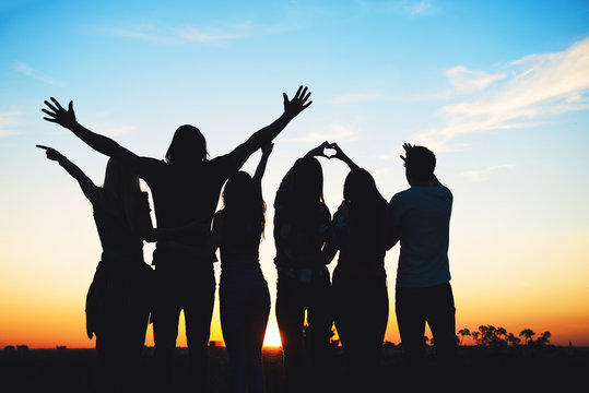 Group of people jumping outdoors; sunset 