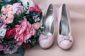 Beautiful wedding shoes with high heels and a bouquet of colorful flowers hydrangea, peonies and roses on a background of kraft paper, decorations, preparing for the wedding, details, boudoir