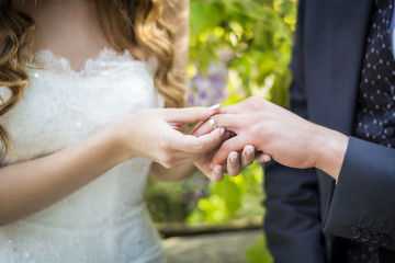 Close-up of bride putting wedding ring on groom's finger