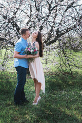 Young couple in love outdoor.Stunning sensual outdoor portrait of young stylish fashion couple posing in spring near blossom tree