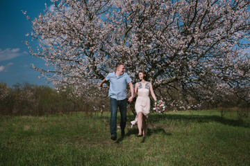 Happy couple running in bloom garden holding hand in hand on blue sky background,smile and have fun,lifestyle,yong