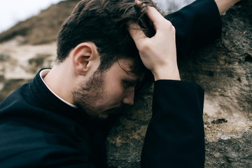 Portrait of handsome catholic bearded man priest or pastor posing outdoors in mountains
