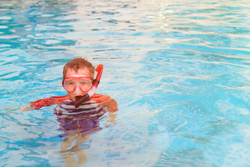 little boy swimming with mask in outdoor pool