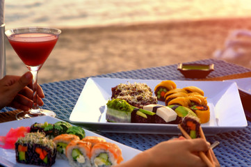The dinner with japanese sushi roll set at the beach on the sunset