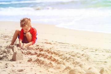 Fototapeta na wymiar little boy play with sand on summer beach