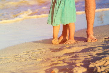 Close up of father and little daughter feet on beach