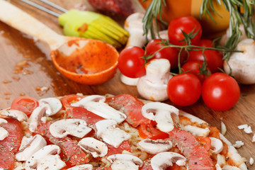 Cooking homemade pizza with salmon, tomatoes and mushrooms