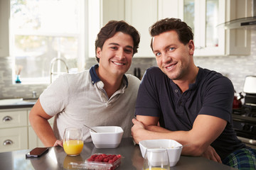 Fototapeta na wymiar Male gay couple having breakfast in kitchen look to camera